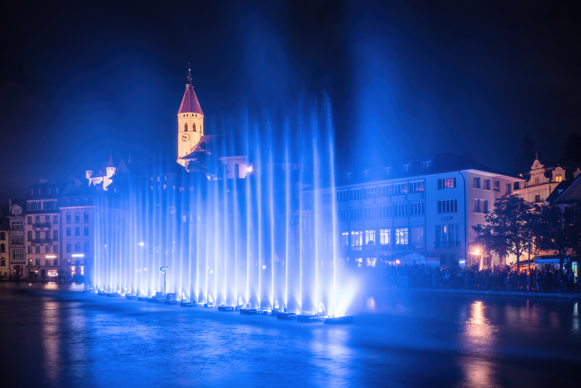Jets d'eau lumineux bleus en bord de lac