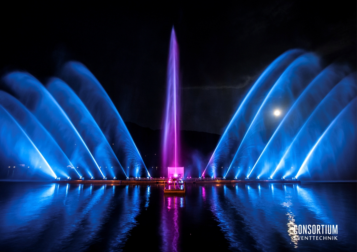 Éventail de jets d'eau bleus et rose sur le lac