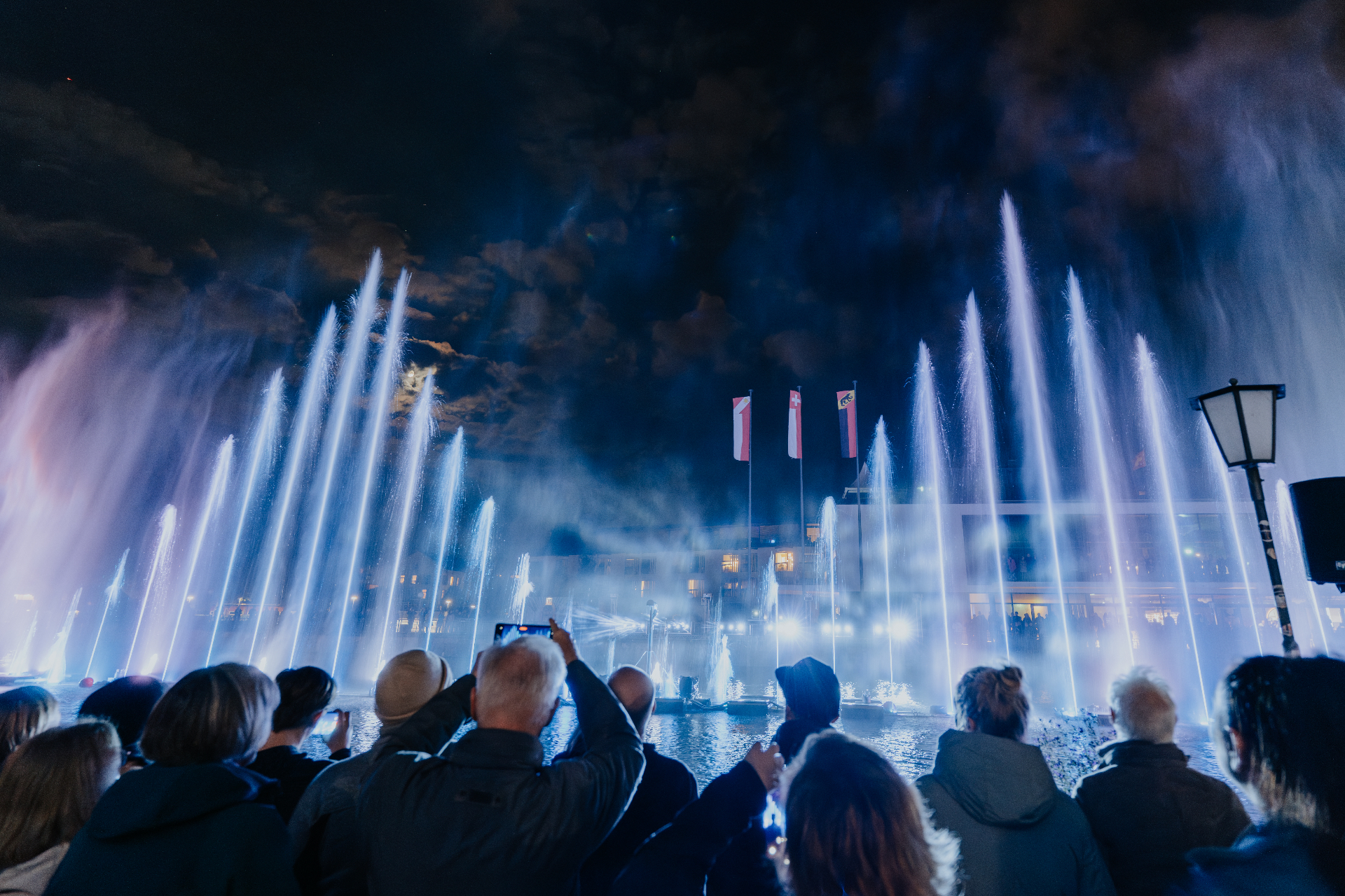 Public admirant le spectacle de fontaines lumineuses